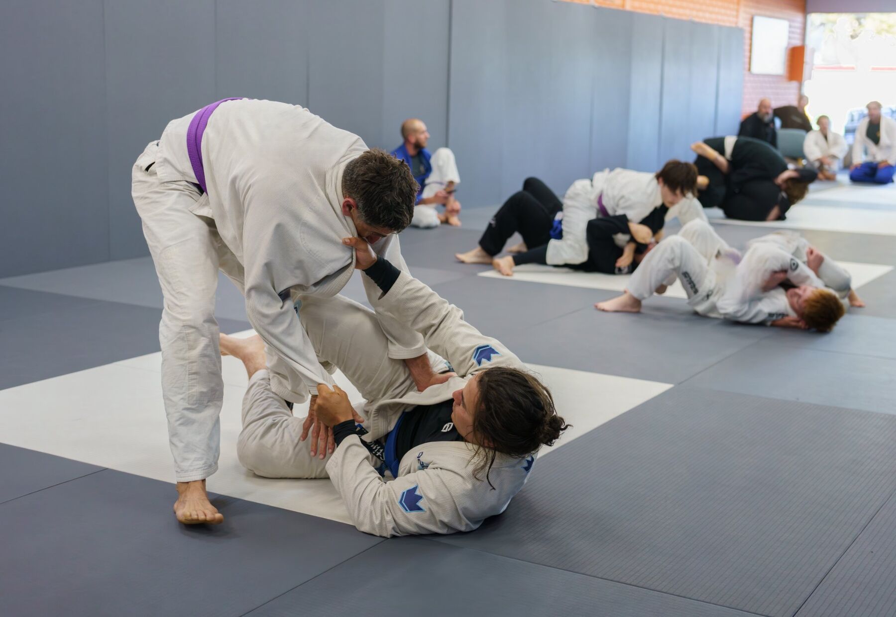 Adults Jiu-Jitsu class rolling on the mats